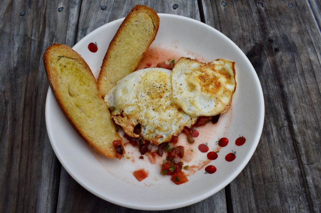 Sauce with tomatoes, olives and capers on eggs