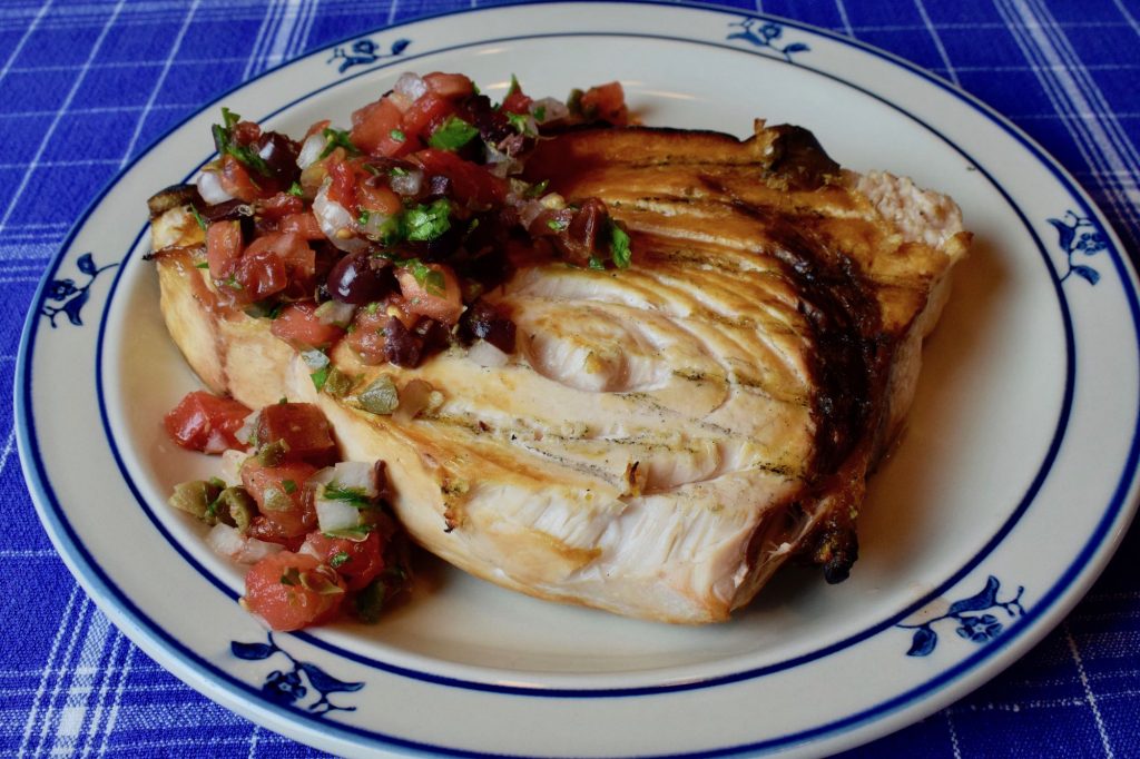Sauce with tomatoes, olives and capers on grilled swordfish