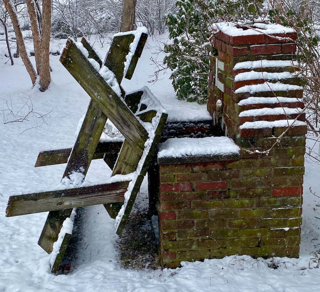 Picnic Table Leaning Against a Fireplace in the Snow