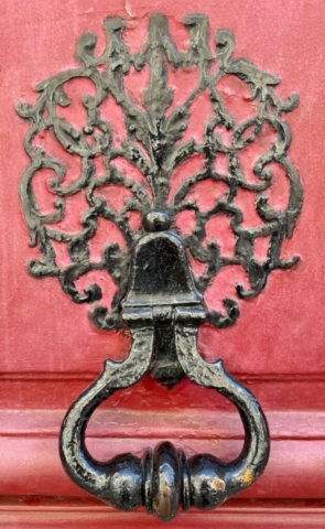 Parisian Door Knocker with a Filigree Mount on a Red Door